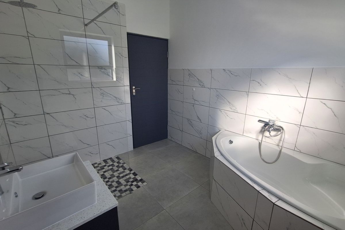 Modern bathroom featuring marble-look wall tiles, a built-in bathtub, a vessel sink vanity, and a walk-in shower area.