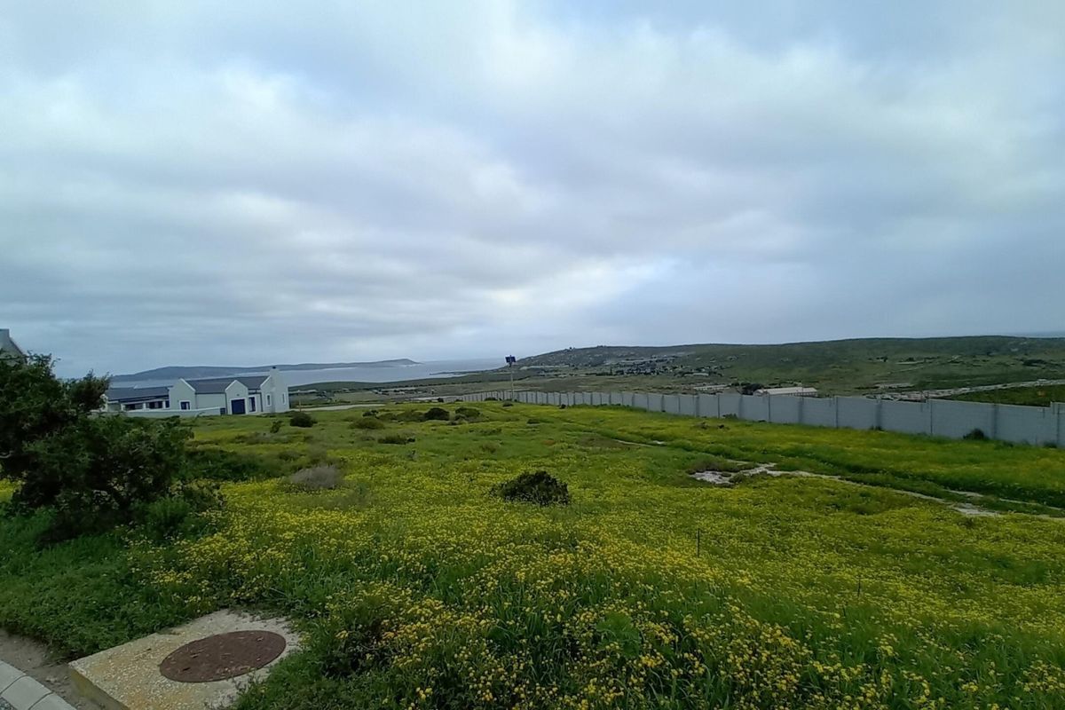 A view of the vacant residential land featuring a boundary wall and surrounding landscape with distant coastal scenery.