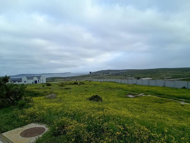 A view of the vacant residential land featuring a boundary wall and surrounding landscape with distant coastal scenery.