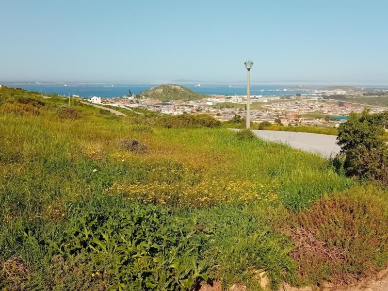 A scenic elevated view overlooking the surrounding landscape, coastal town, and ocean horizon from the vacant residential plot.