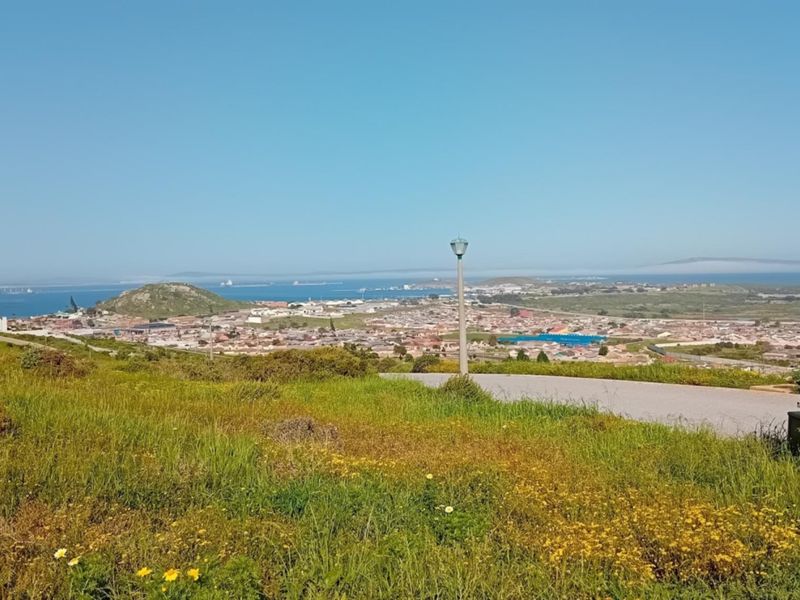 A scenic elevated view overlooking the surrounding residential area, coastline, and ocean horizon from the vacant land plot.
