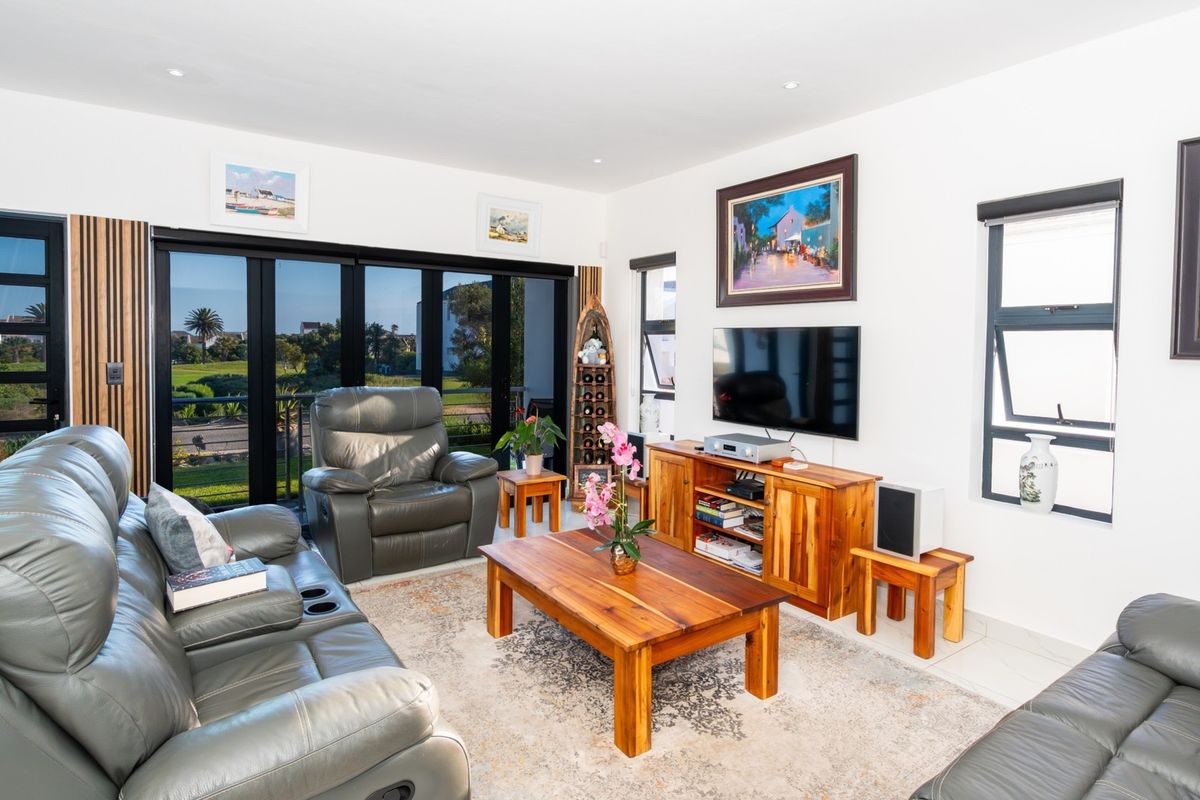 A bright and well-maintained living room featuring large aluminium sliding doors that provide ample natural light and access to the outdoor area.