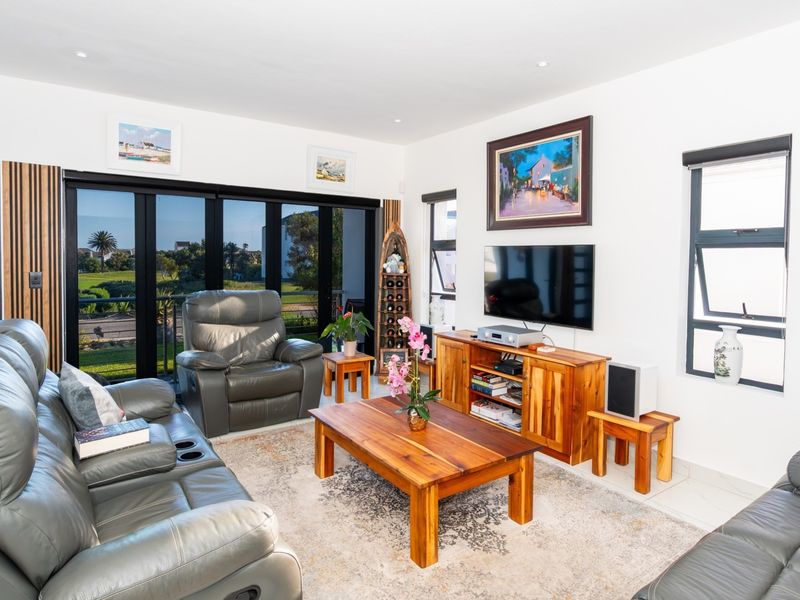 A bright and well-maintained living room featuring large aluminium sliding doors that provide ample natural light and access to the outdoor area.