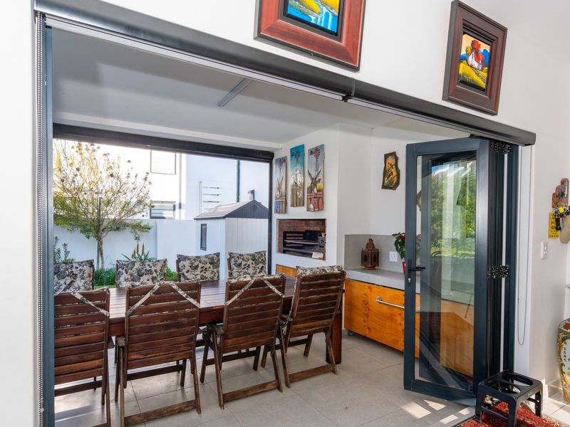 Covered patio area featuring built-in braai, cabinetry, and large stacking doors that open to the rear garden.