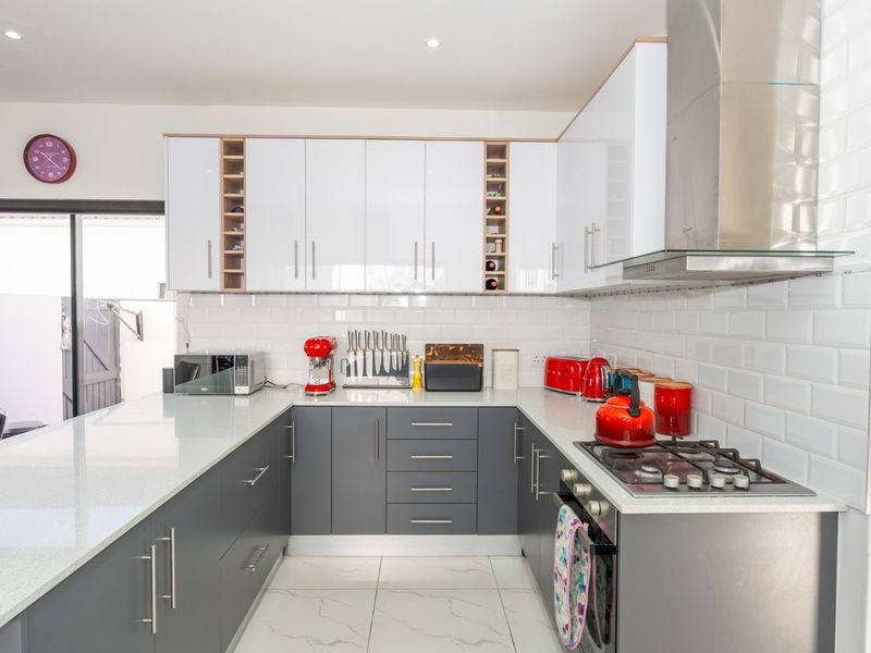 Modern U-shaped kitchen featuring grey cabinetry, white quartz countertops, subway tile backsplash, and integrated stainless steel appliances.