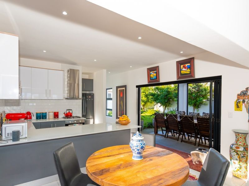 Modern open-plan kitchen featuring a central island, sleek cabinetry, and seamless indoor-outdoor flow through large sliding glass doors to the patio.