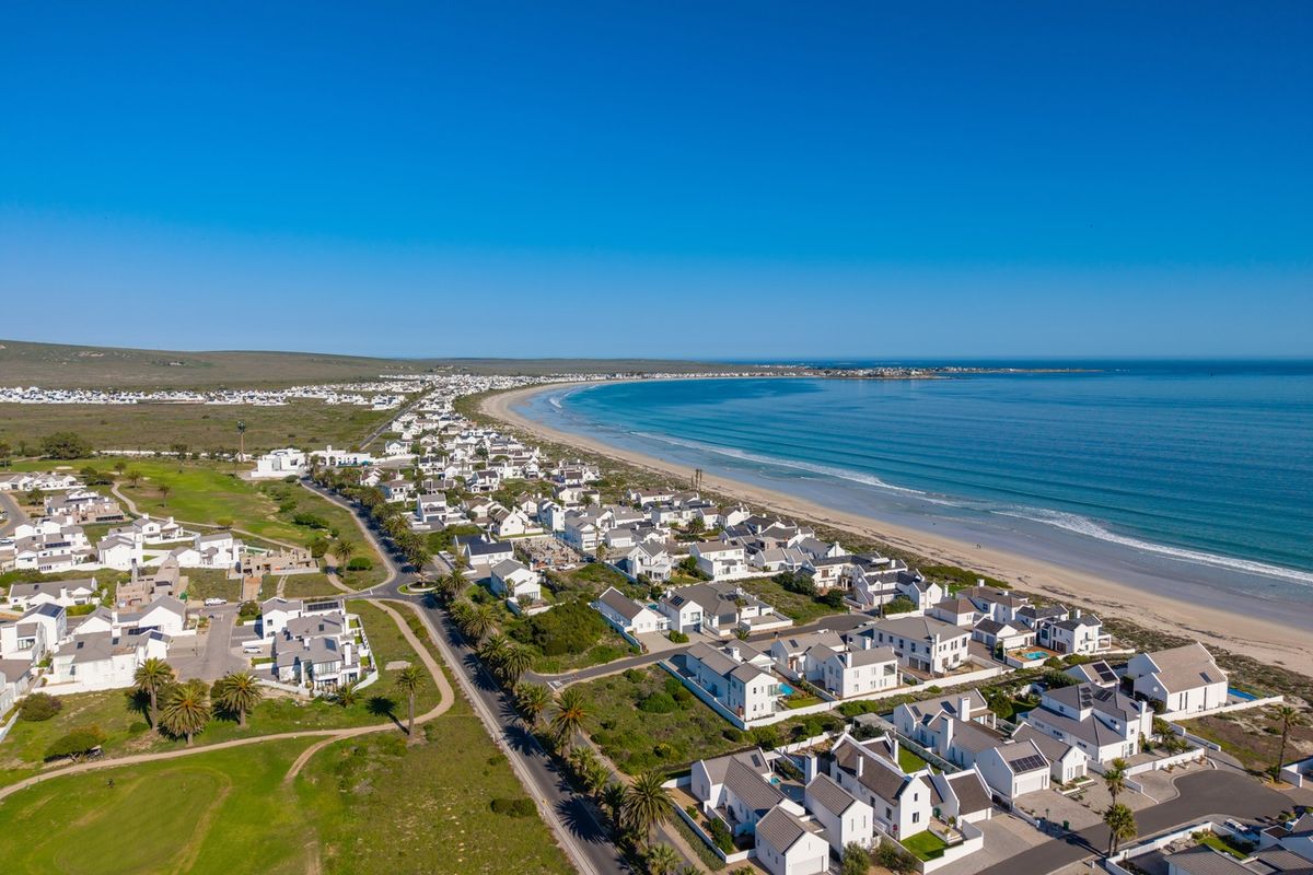 An expansive aerial view of a coastal residential estate situated along a pristine beach and ocean coastline.