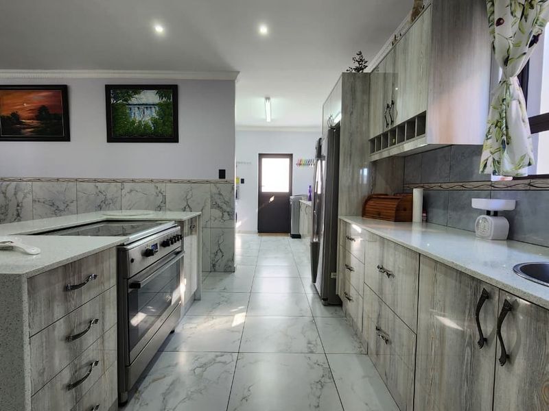 Modern kitchen featuring stone countertops, built-in cabinetry, stainless steel stove, and tiled flooring with a clean, functional layout.