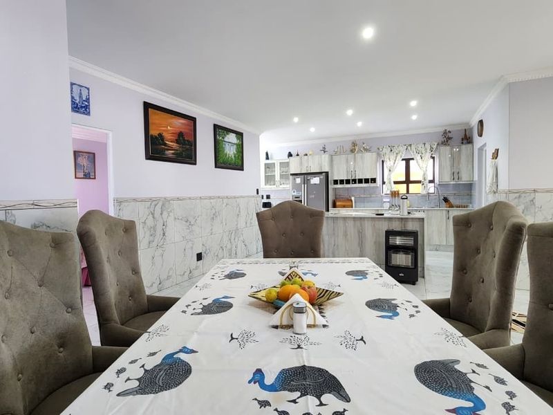 Open-plan dining and kitchen area featuring marble-effect wall tiling, recessed lighting, and modern fitted cabinetry.