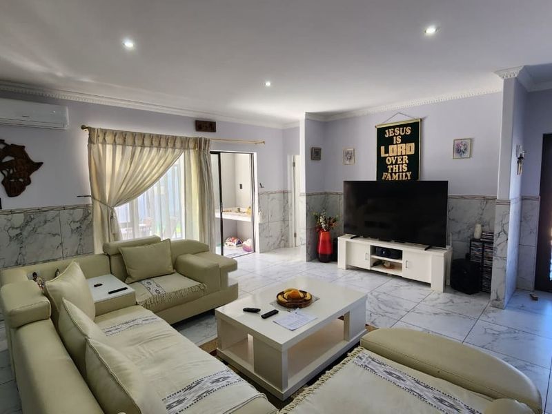 Spacious living room featuring marble-look tiled flooring and wall wainscoting, recessed lighting, and a split-system air conditioner.