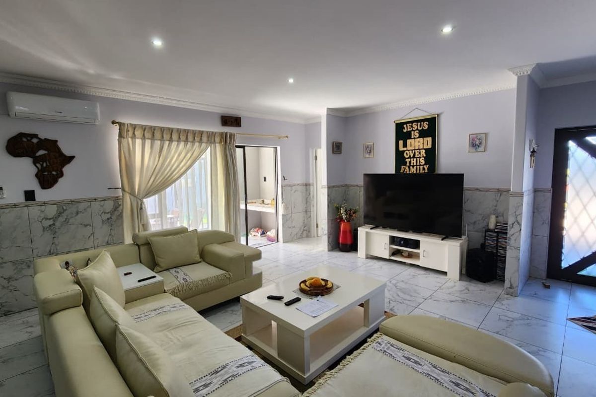 Spacious living room featuring marble-look tiled flooring and wall wainscoting, recessed lighting, and a split-system air conditioner.