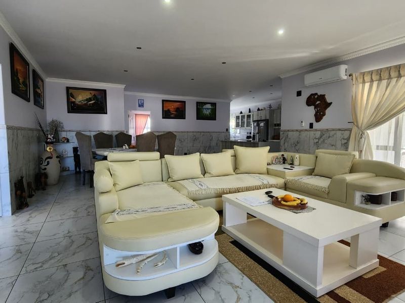 Spacious open-plan living and dining area featuring marble-look tiled flooring, recessed lighting, and direct access to the patio through sliding glass doors.