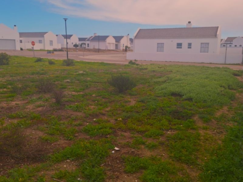 A vacant residential plot of land situated in a developed estate, featuring perimeter fencing and views of neighboring properties.