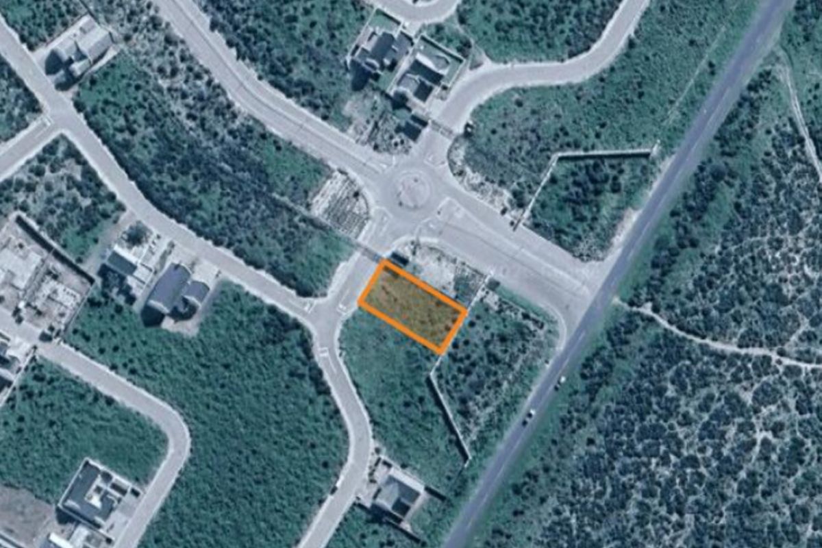 Aerial view of a vacant residential corner plot situated within a developed estate, offering convenient road access and proximity to local infrastructure.
