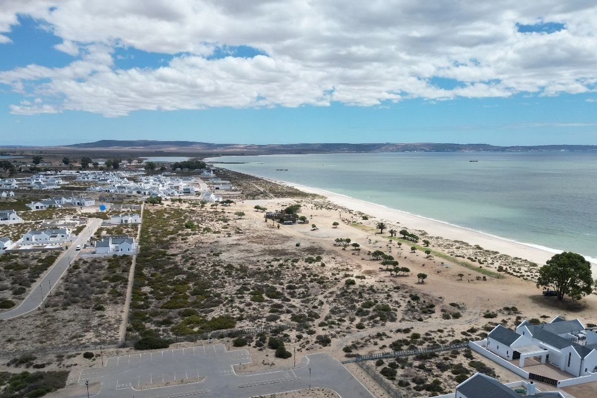 An aerial view of the coastal residential area, showcasing the proximity to the beach, surrounding landscape, and local infrastructure.