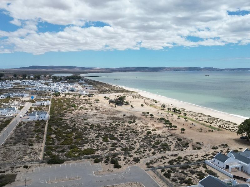 An aerial view of the coastal residential area, showcasing the proximity to the beach, surrounding landscape, and local infrastructure.