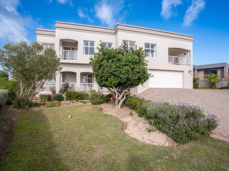 A well-maintained double-story residential property featuring a paved driveway, double garage, and landscaped front garden with balconies on the upper level.