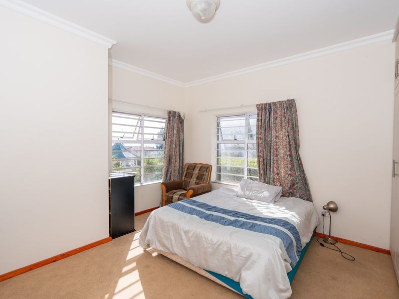 A bedroom featuring built-in cupboards, carpet flooring, and louver windows that provide natural light.