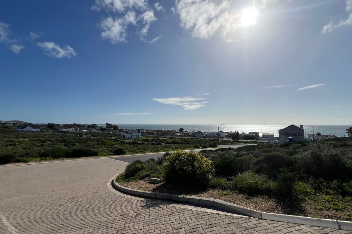 A wide-angle view of the coastal landscape and surrounding residential area, featuring a paved driveway in the foreground.