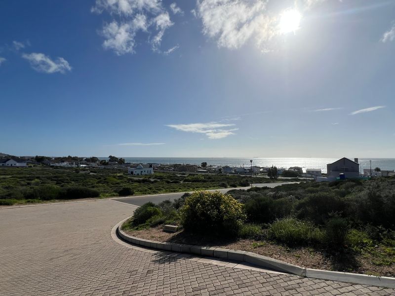 A wide-angle view of the coastal landscape and surrounding residential area, featuring a paved driveway in the foreground.