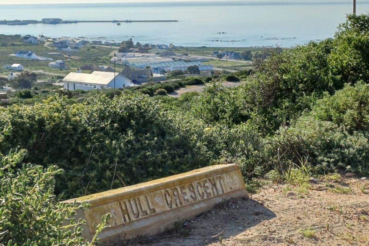 A scenic elevated view overlooking the coastal landscape and nearby residential area, featuring a street sign for Hull Crescent in the foreground.