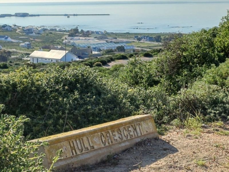 A scenic elevated view overlooking the coastal landscape and nearby residential area, featuring a street sign for Hull Crescent in the foreground.