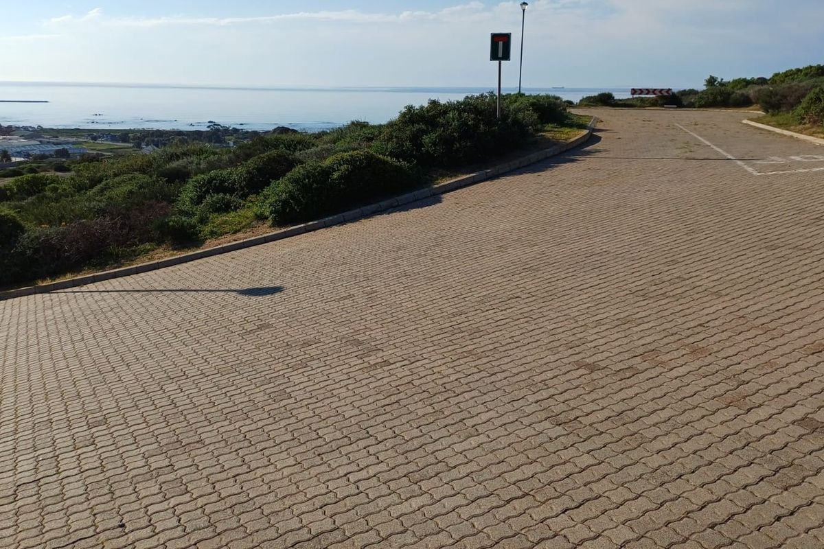 A paved street view showing the approach to the property with coastal landscape views in the background.