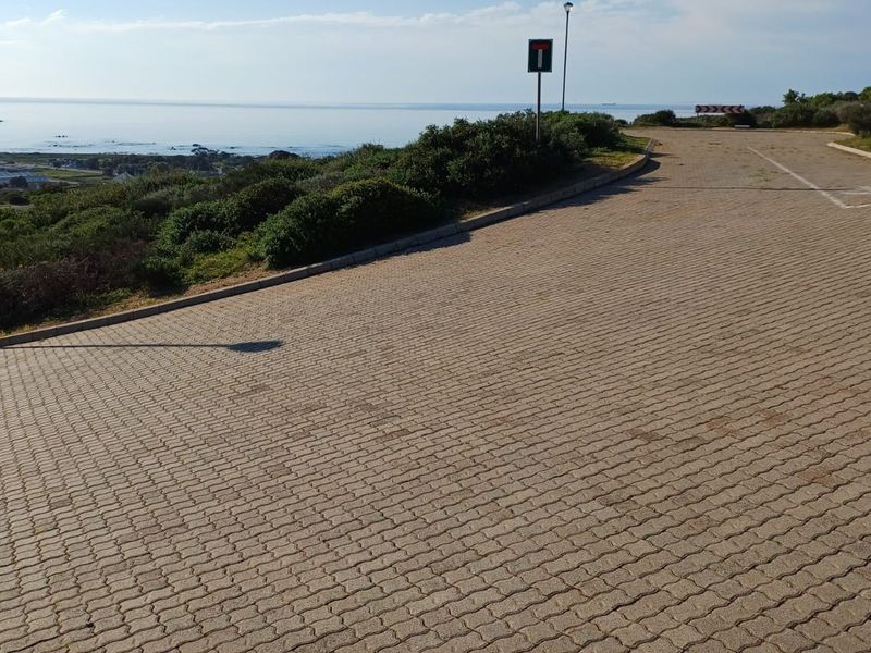 A paved street view showing the approach to the property with coastal landscape views in the background.