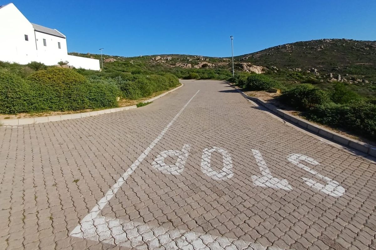 A view of the paved residential street approach with clear road markings and surrounding natural landscape.