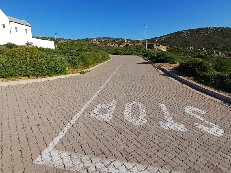 A view of the paved residential street approach with clear road markings and surrounding natural landscape.