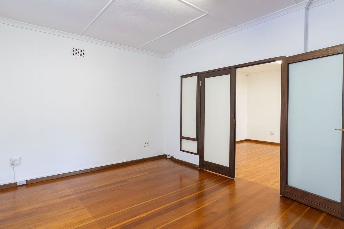 An empty living room featuring polished timber flooring and elegant frosted glass double doors leading to an adjacent space.