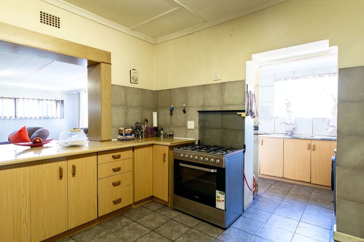 Functional kitchen featuring built-in cabinetry, laminate countertops, and a gas stove, with an adjoining scullery area and tiled flooring throughout.