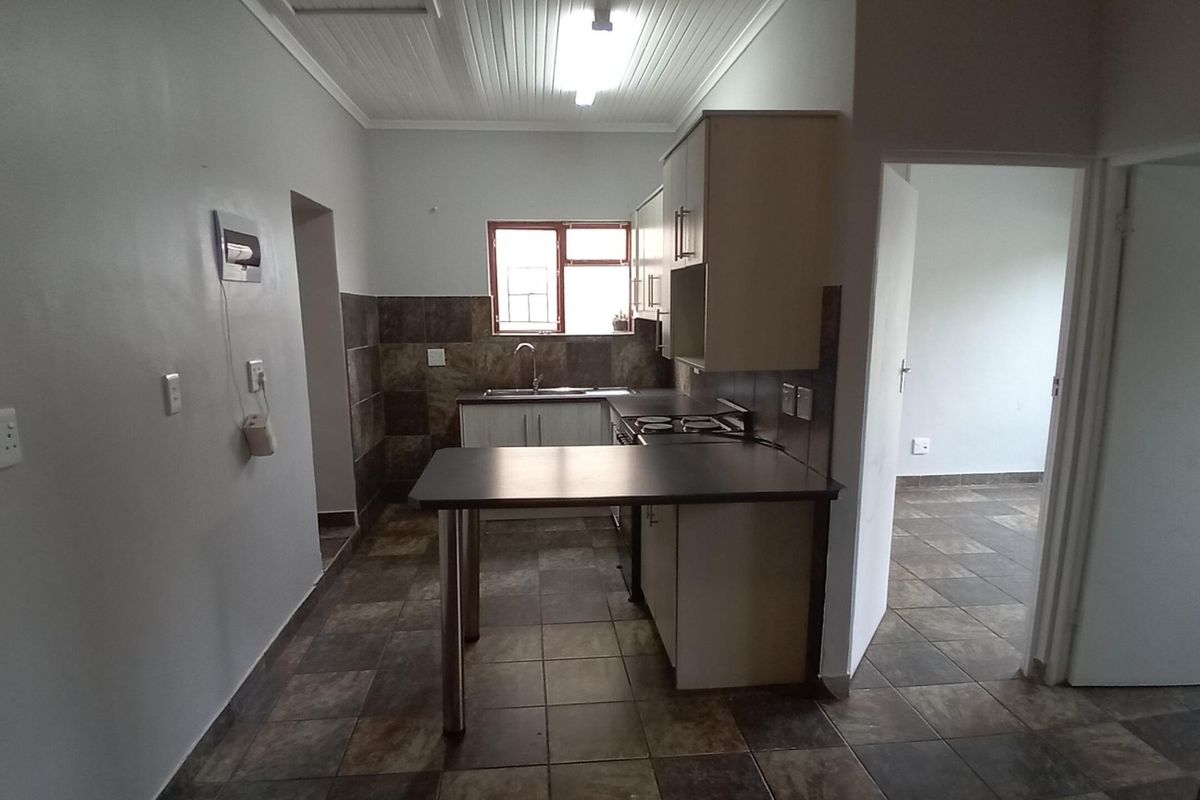 A functional kitchen featuring built-in cabinetry, a breakfast bar, tiled backsplash, and tiled flooring, offering a clean and practical layout.