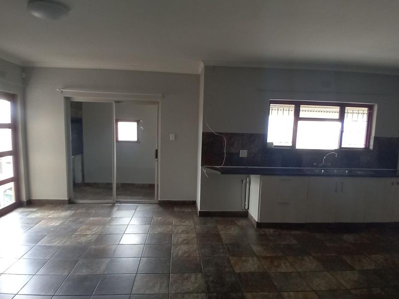 An open-plan living and kitchen area featuring tiled flooring, built-in cabinetry, and a sliding door leading to an adjacent space.