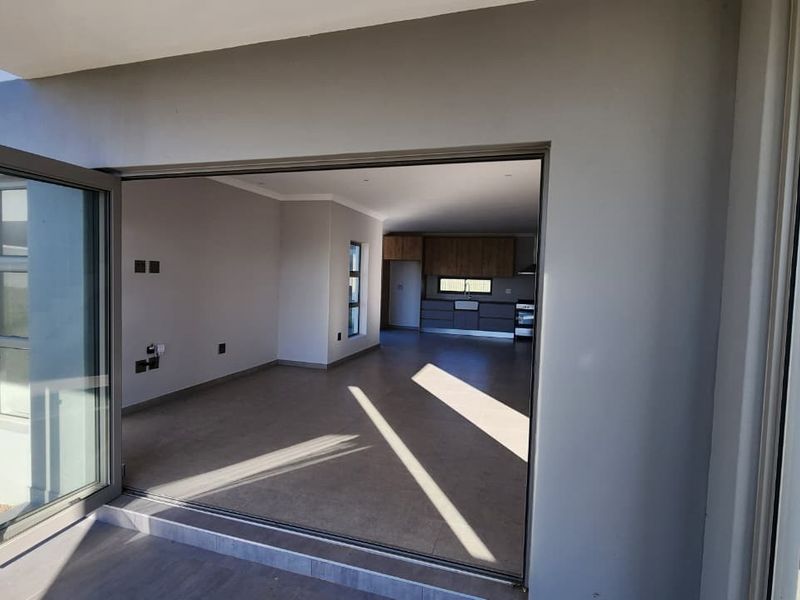 Spacious open-plan living and kitchen area featuring modern tiled floors, recessed lighting, and large bi-fold doors opening to the exterior.
