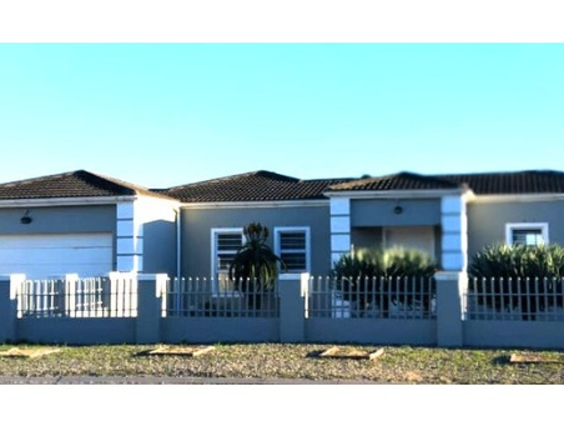 Front elevation of a single-story residential house featuring a tiled roof, double garage, and a secure perimeter wall with metal fencing.