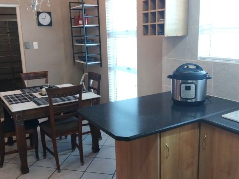 Open plan kitchen and dining area featuring tiled flooring, laminate cabinetry, and dark countertops, providing a functional space for cooking and casual dining.