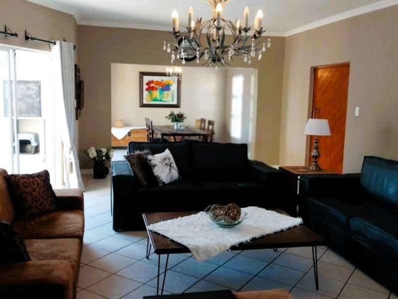 Spacious living room featuring tiled flooring, a decorative chandelier, and direct access to the outdoor area through a sliding glass door.
