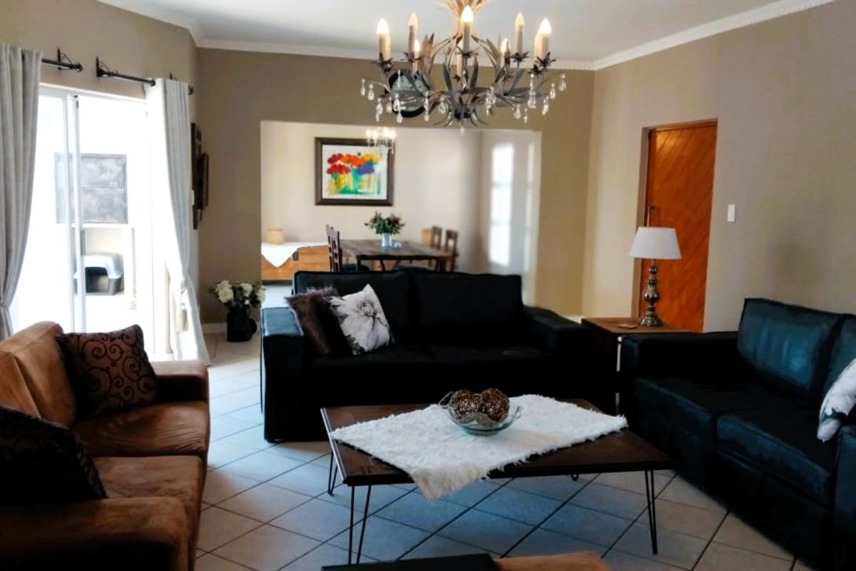 Spacious living room featuring tiled flooring, a decorative chandelier, and direct access to the outdoor area through a sliding glass door.