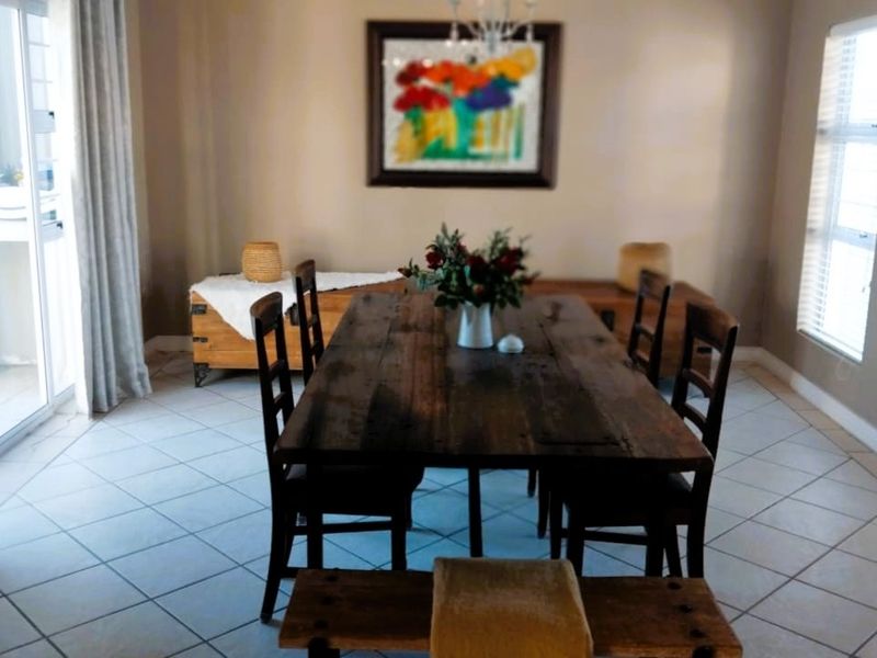 A dining room featuring tiled flooring, a chandelier, and natural light from large windows and a sliding glass door leading to the exterior.