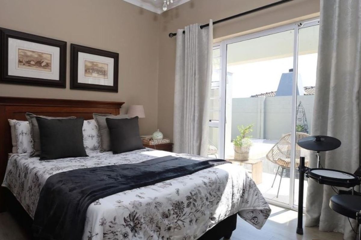 A well-maintained bedroom featuring laminate flooring and a large sliding glass door providing direct access to an outdoor patio area.