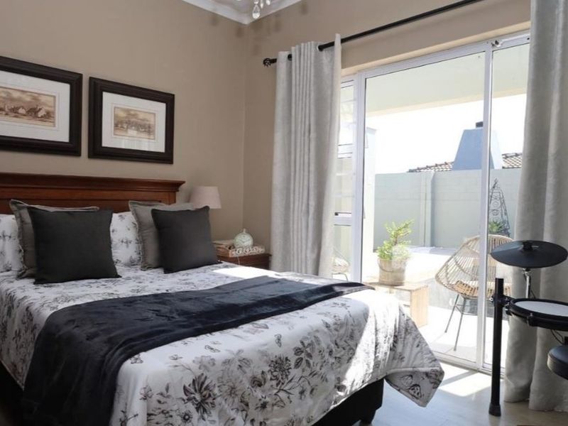 A well-maintained bedroom featuring laminate flooring and a large sliding glass door providing direct access to an outdoor patio area.