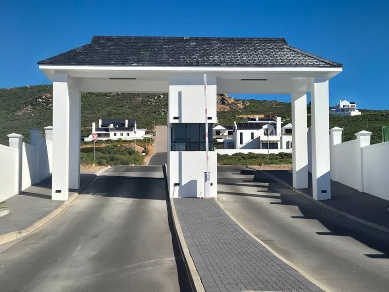 A modern, well-maintained security gatehouse entrance for a residential estate, featuring a paved driveway and perimeter walling.