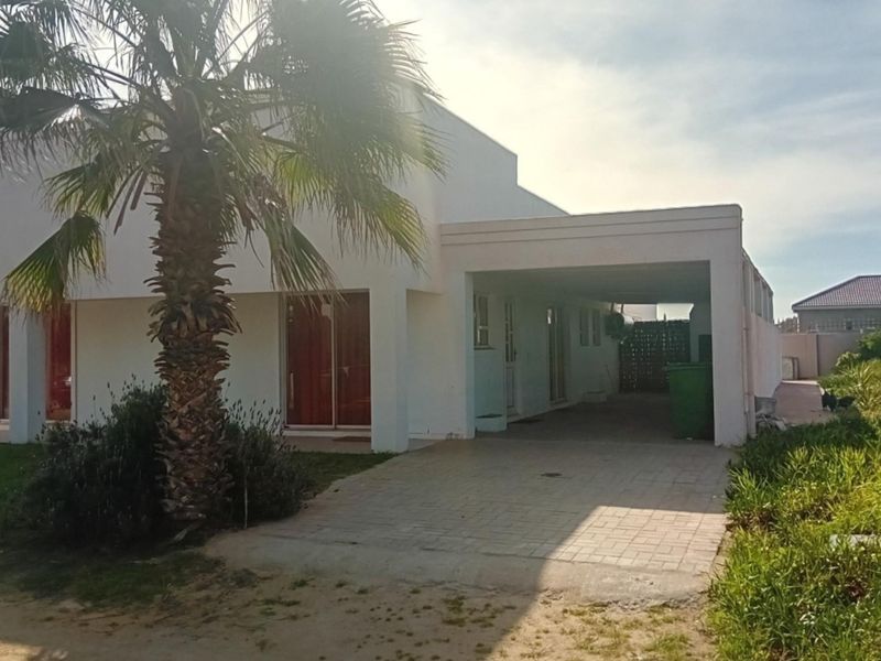 Front exterior view of a single-story house featuring a paved driveway, integrated carport, and sliding glass door access.