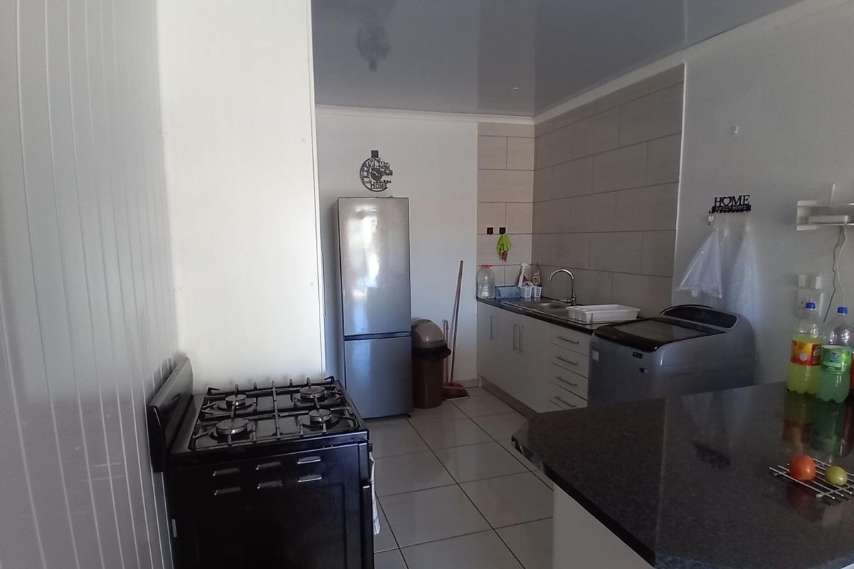 A functional kitchen featuring tiled flooring, built-in cabinetry, a gas stove, and a tiled backsplash with a stainless steel sink.