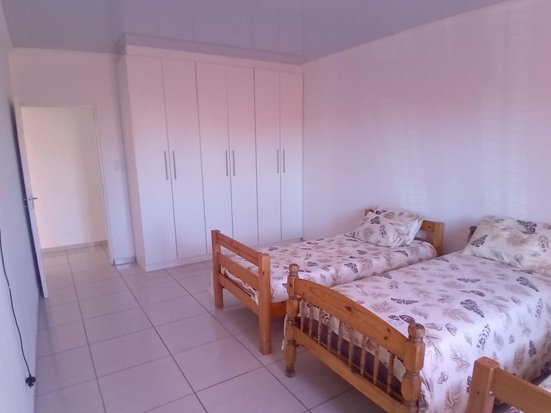 A bedroom featuring tiled flooring and ample built-in cupboard storage space.