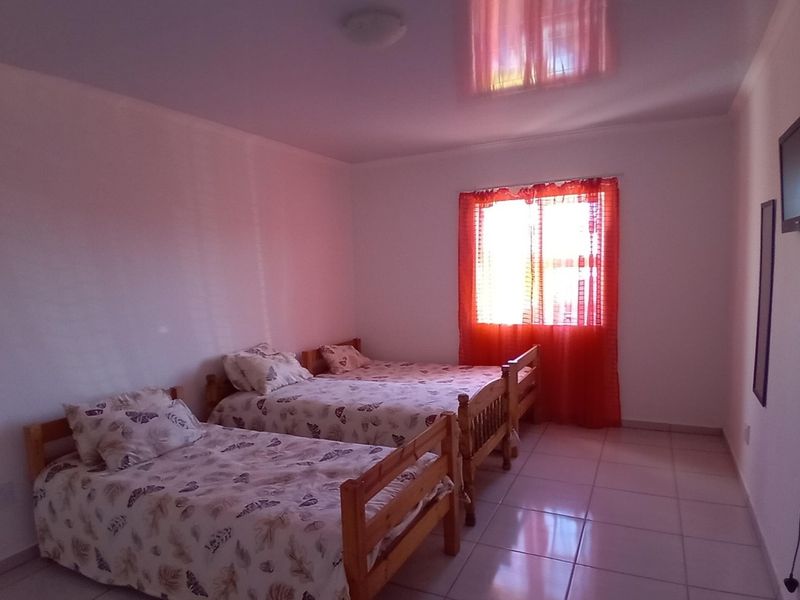 A bedroom featuring tiled flooring and a glossy ceiling finish, providing a functional space with natural light from the window.