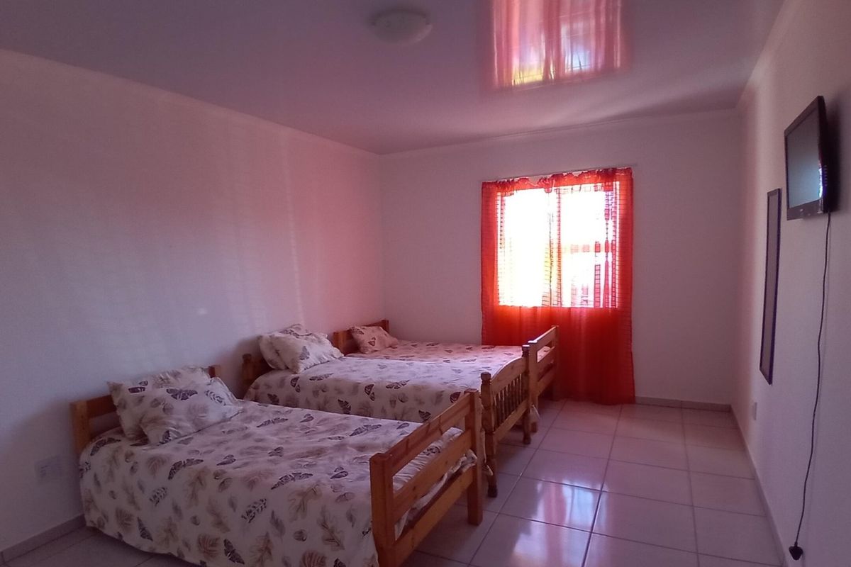 A bedroom featuring tiled flooring and a glossy ceiling finish, providing a functional space with natural light from the window.