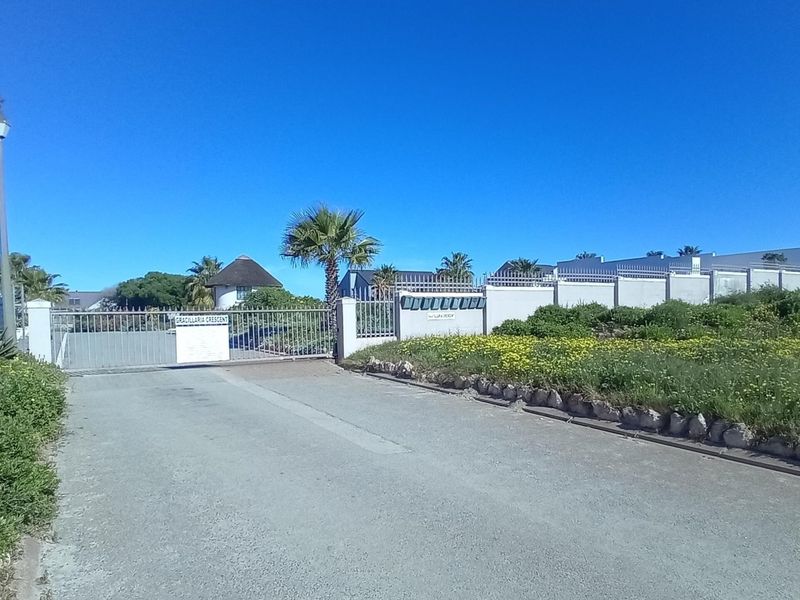 A view of the gated entrance to the residential estate, featuring a security gate, perimeter wall, and communal post boxes.