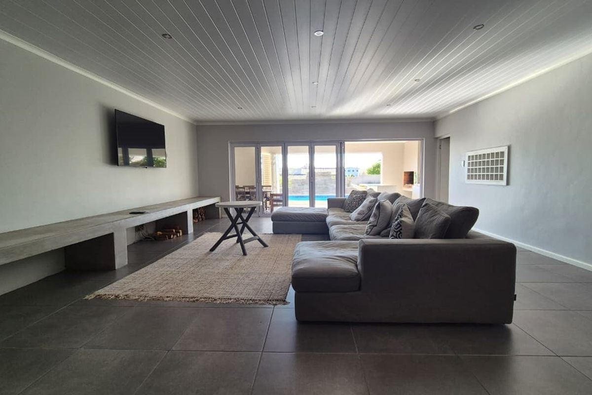 Spacious living room featuring tiled floors, a built-in concrete media console, and bi-fold doors opening to an outdoor pool area.